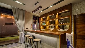 A bar area with a wooden counter, three bar stools, and a large mirror with circular frames. - Fishermen Pool Villa Samui (Chang Wat Surat Thani)