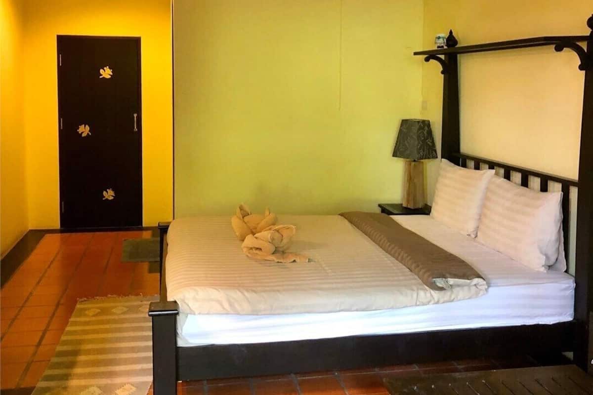 A bedroom with a bed, a nightstand, a lamp, and a door with floral decorations.