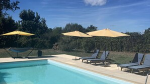 A swimming pool with lounge chairs and umbrellas, surrounded by greenery. - Le Petit Comte' an Oasis of Calm with heated pool and hot tub in 2.5 acres (Bergerac)