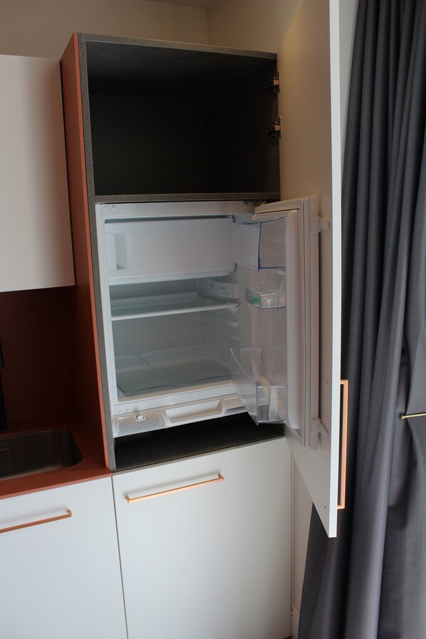 A compact kitchen with a built-in refrigerator, a sink, and a countertop.