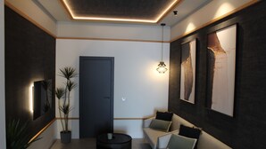 A modern interior with a sofa, a round coffee table, and potted plants. - Promotur Suites - Ayora (Valencia)