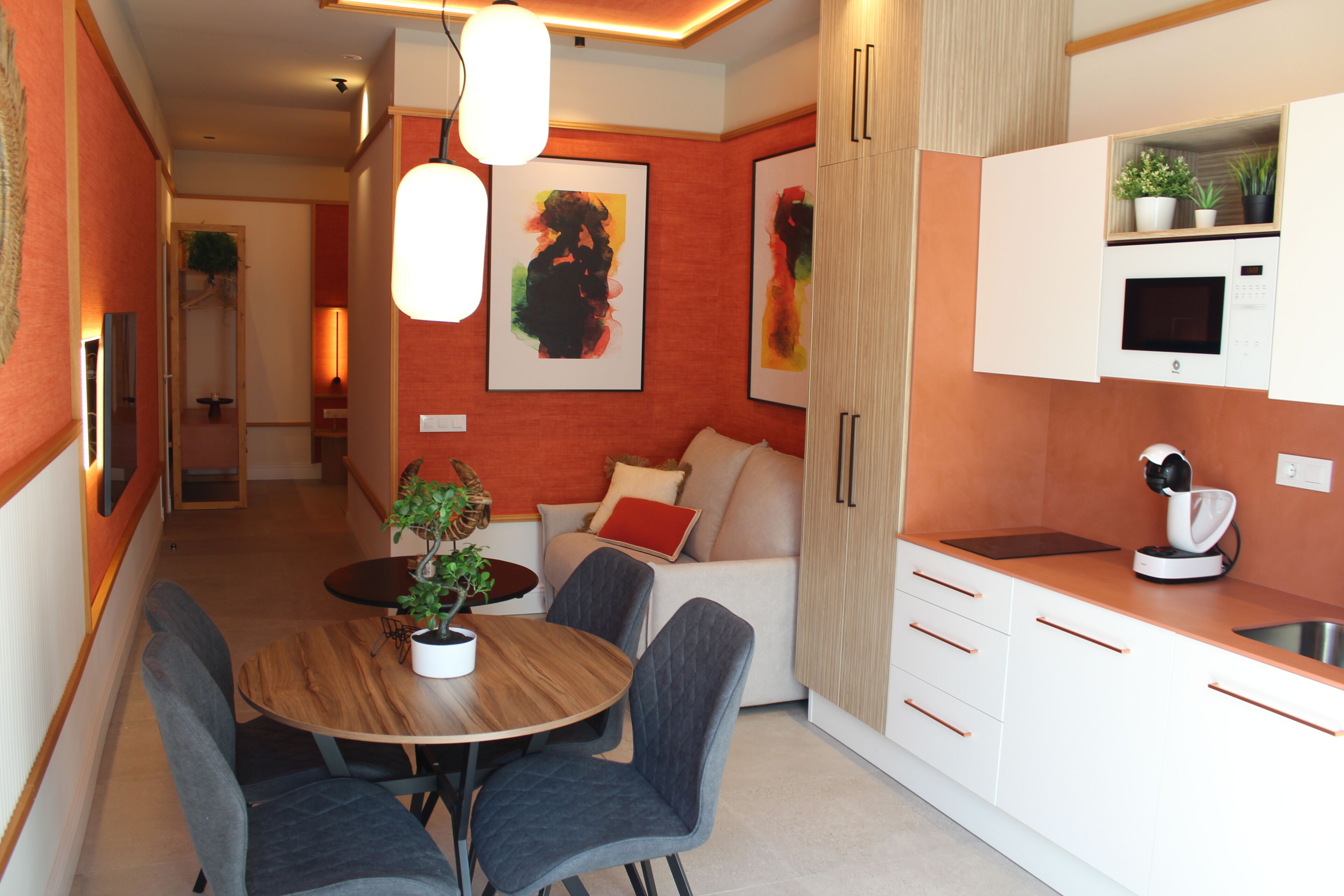 A modern kitchen with white cabinets, a dining table with chairs, and a microwave.