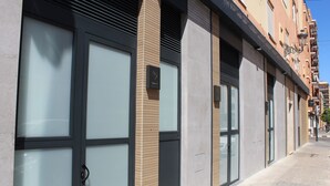 A building with large glass doors, a tiled sidewalk, and a clear sky. - Promotur Suites - Ayora (Valencia)