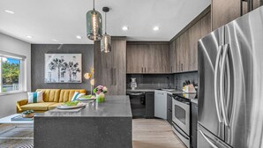 A modern kitchen with a central island, stainless steel appliances, and a view of the outdoors. - 261 #5 Managed By Brampton Park (Deerfield Beach)