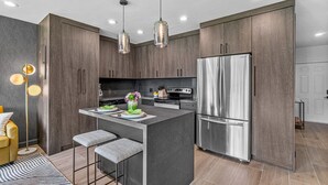 A modern kitchen with dark wood cabinets, stainless steel appliances, and pendant lighting. - 261 #5 Managed By Brampton Park (Deerfield Beach)