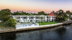 Um hotel à beira-mar com piscina, várias varandas e vegetação exuberante.
