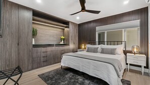 Une chambre moderne avec un lit, des tables de chevet, un ventilateur de plafond et des rangements intégrés.