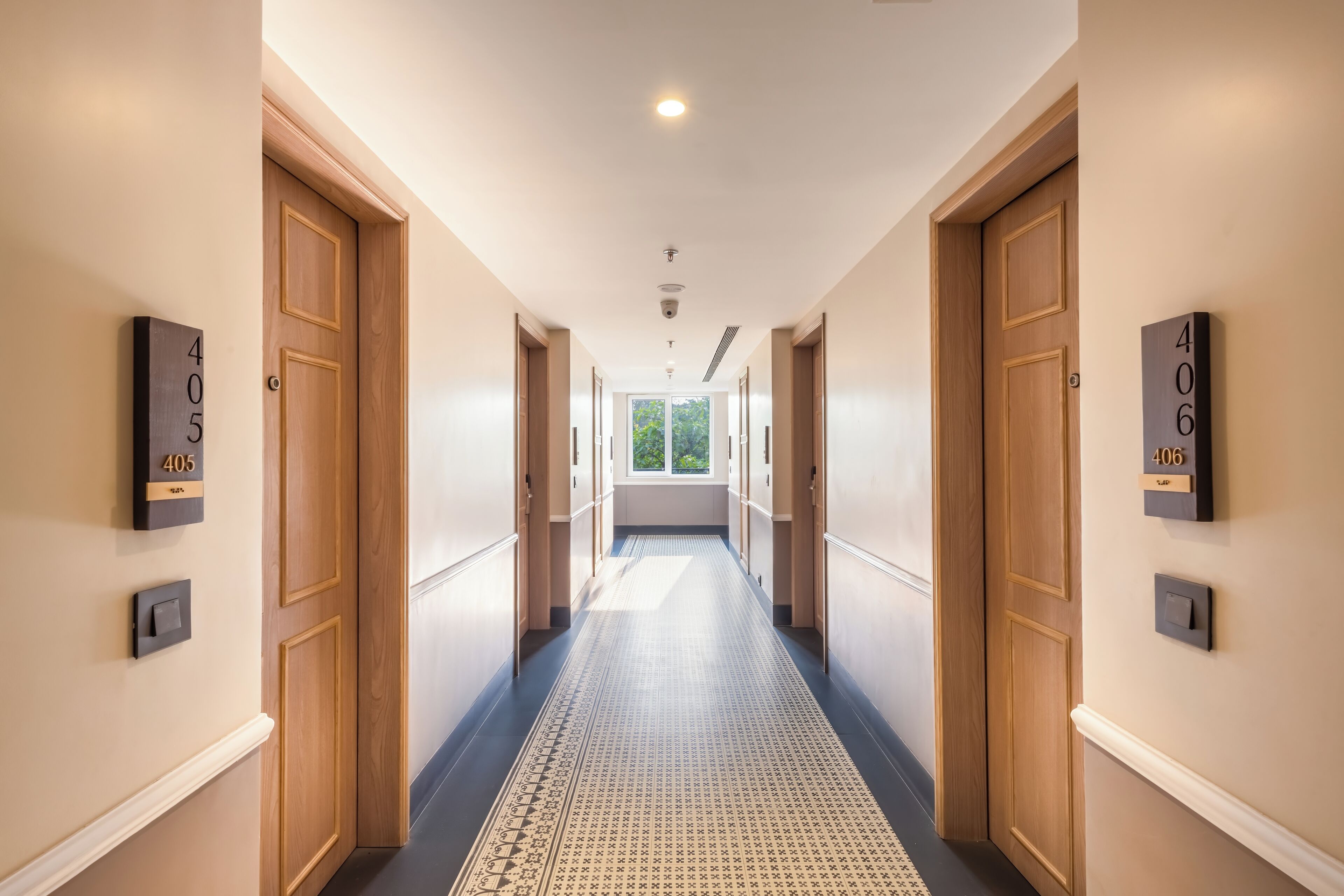 A hotel hallway with wooden doors, numbered room signs, and a patterned carpet.