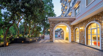 Un pasillo de hotel con arcos de piedra, plantas en macetas y un camino empedrado.