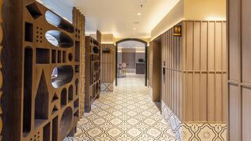 Un pasillo con baldosas de diseño, paneles decorativos de madera y un letrero que indica el baño de hombres.