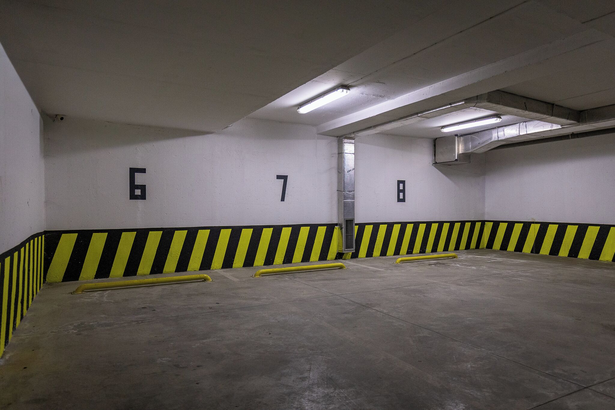 Un estacionamiento con espacios numerados y barreras de seguridad amarillas.