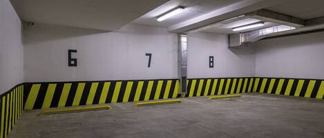Un estacionamiento con espacios numerados y barreras de seguridad amarillas.