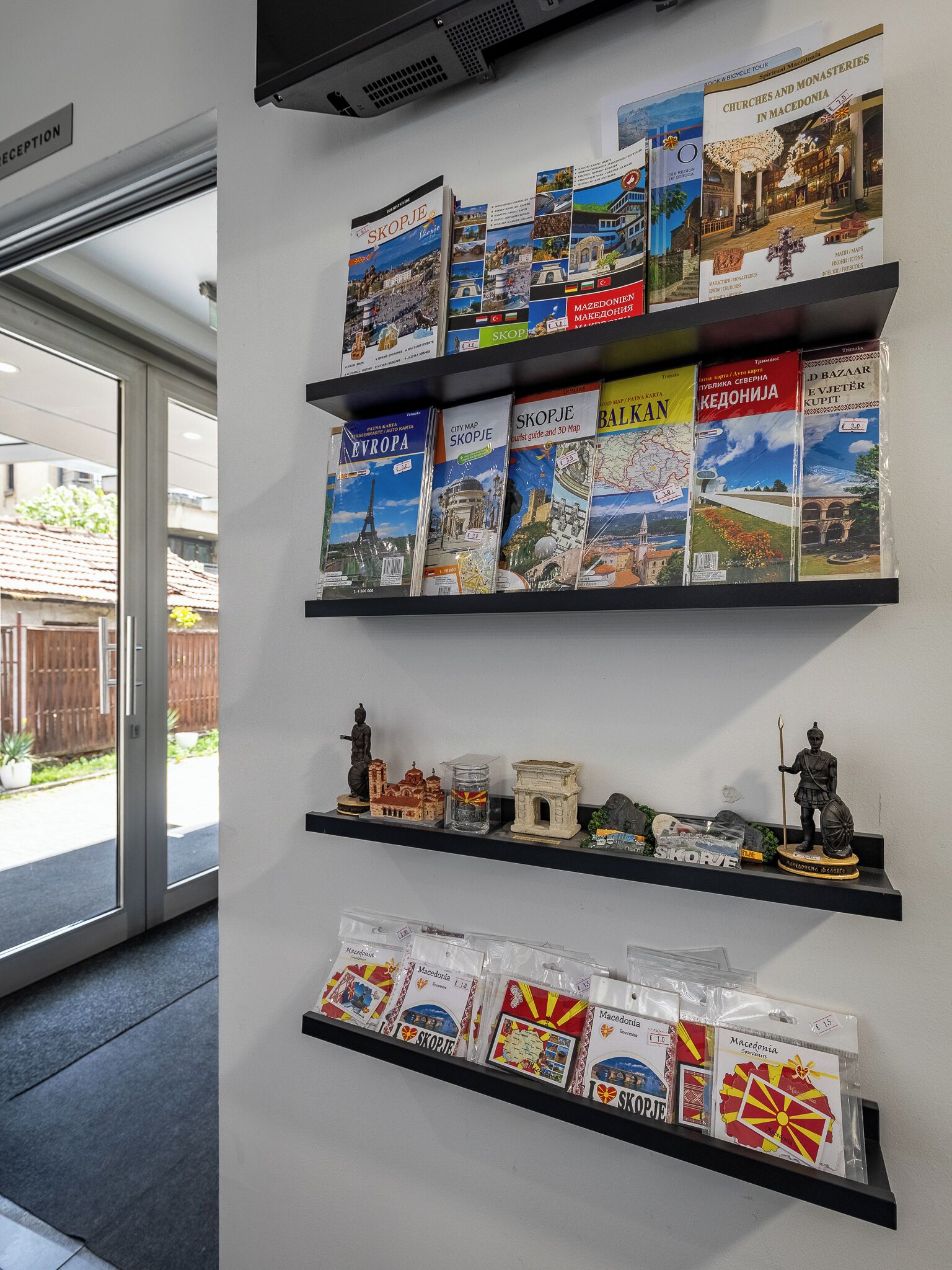 A wall with shelves displaying travel books and souvenirs.