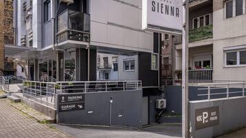 Ein modernes Gebäude mit einem Schild für 'Sienna', das es als Hotel kennzeichnet. Es gibt Schilder für 'PARKING' und 'GARAGE' mit Nummern.