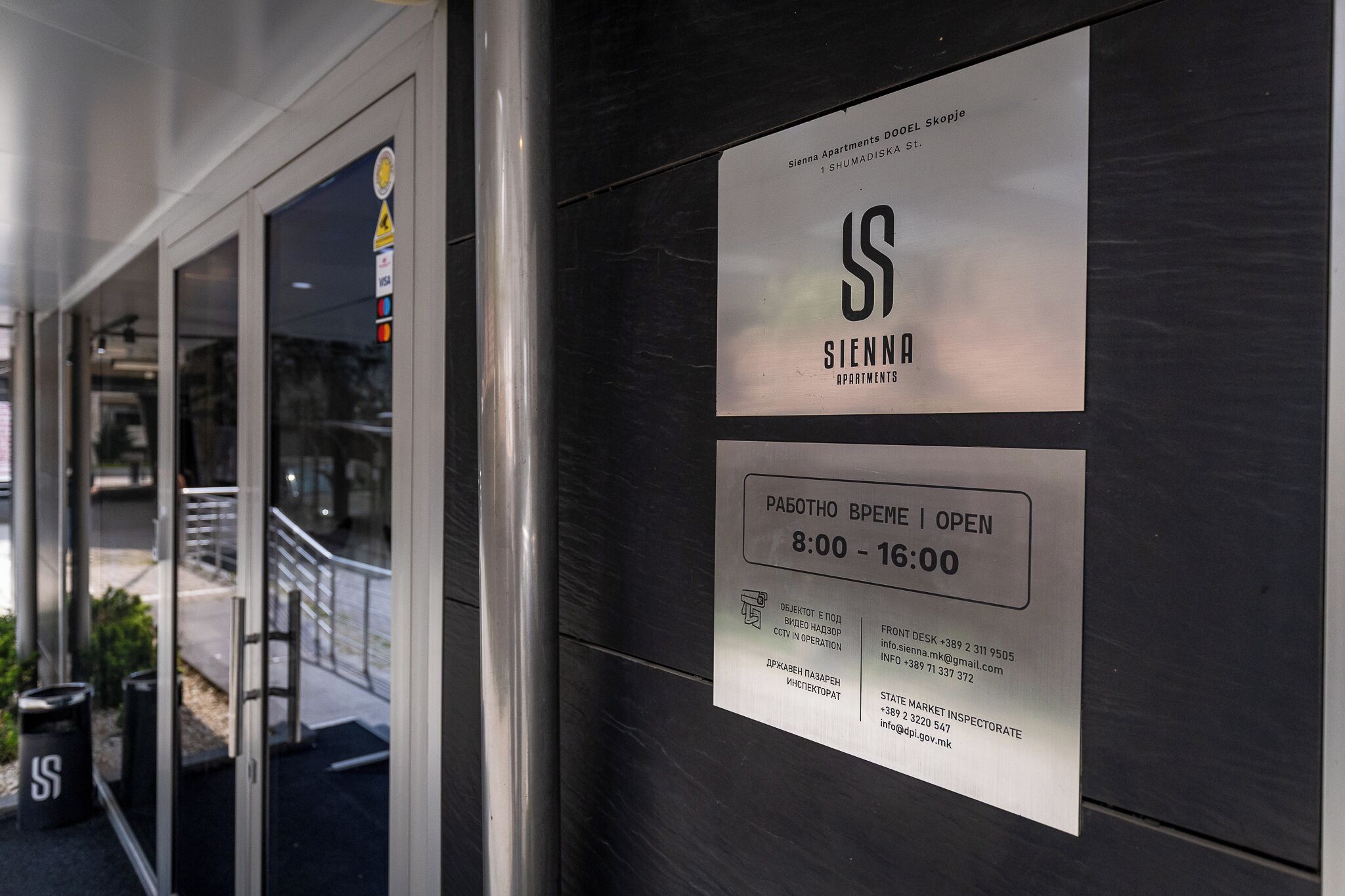 A sign for Sienna Apartments with operating hours and contact information.