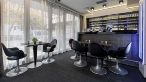 Un interior moderno con una zona de bar, sillas negras y una exhibición de objetos en estanterías.