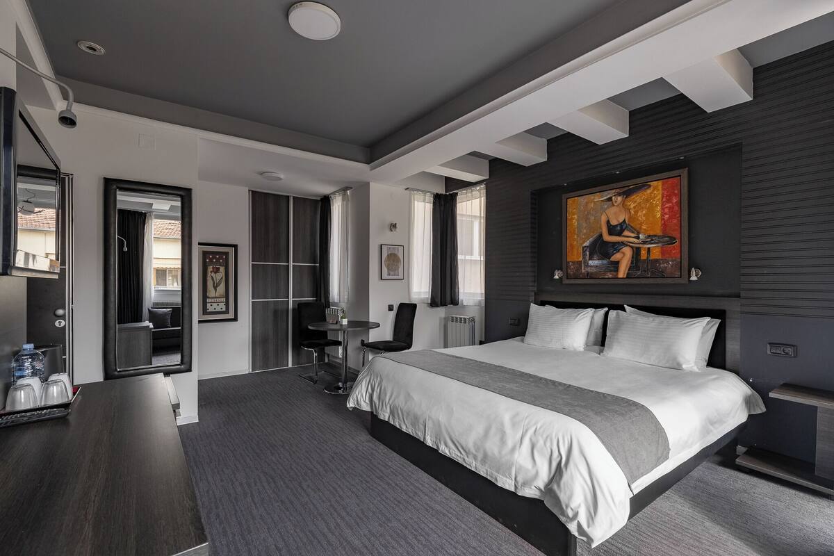 Een moderne hotelkamer met een groot bed, een bureau, een stoel en een schilderij aan de wand.