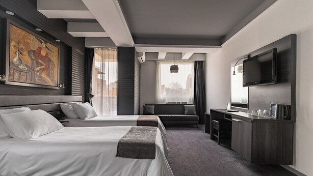 Habitación de hotel con dos camas, un escritorio, un televisor y un cuadro en la pared.