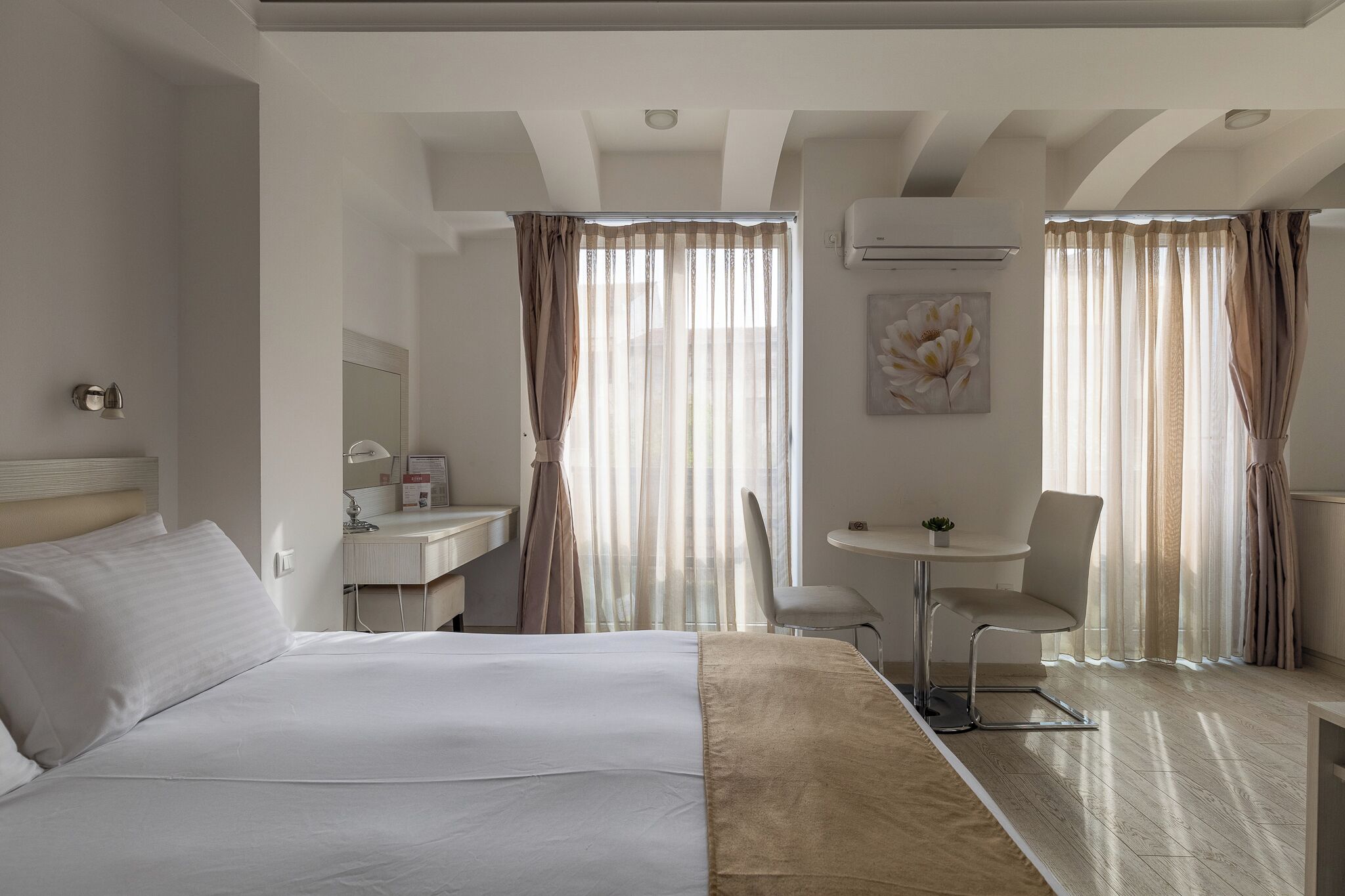 A hotel room with a bed, a desk, a chair, and a small table.