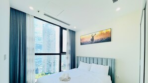 Une chambre d’hôtel avec un grand lit, une vue sur la ville et un tableau au mur.