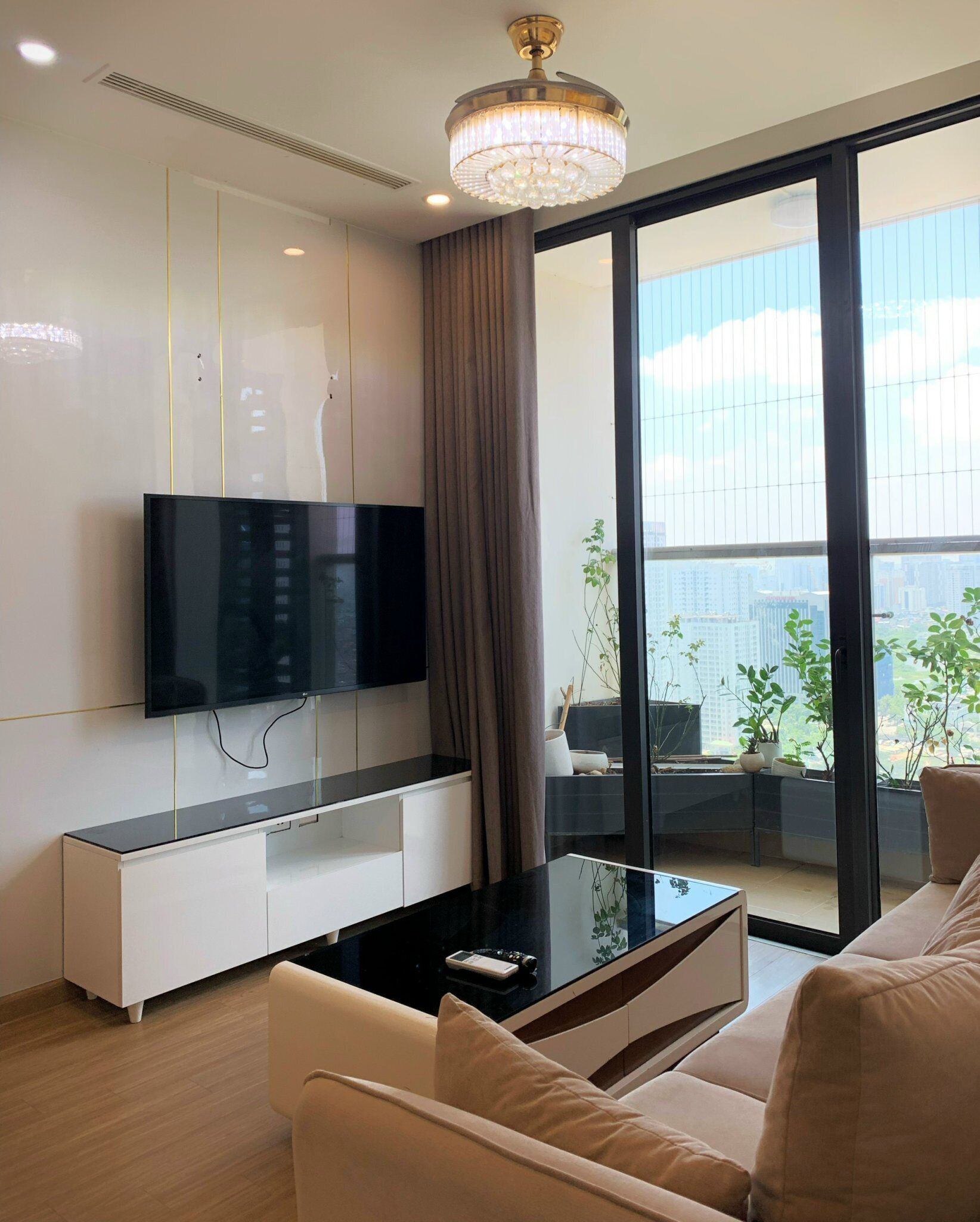 Ein modernes Wohnzimmer mit Flachbildfernseher, Glastisch und Sofa.