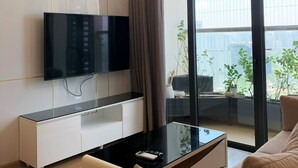 Un salon moderne avec un téléviseur à écran plat, une table basse en verre et un canapé.