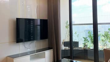 Ein modernes Wohnzimmer mit Flachbildfernseher, Glastisch und Sofa.