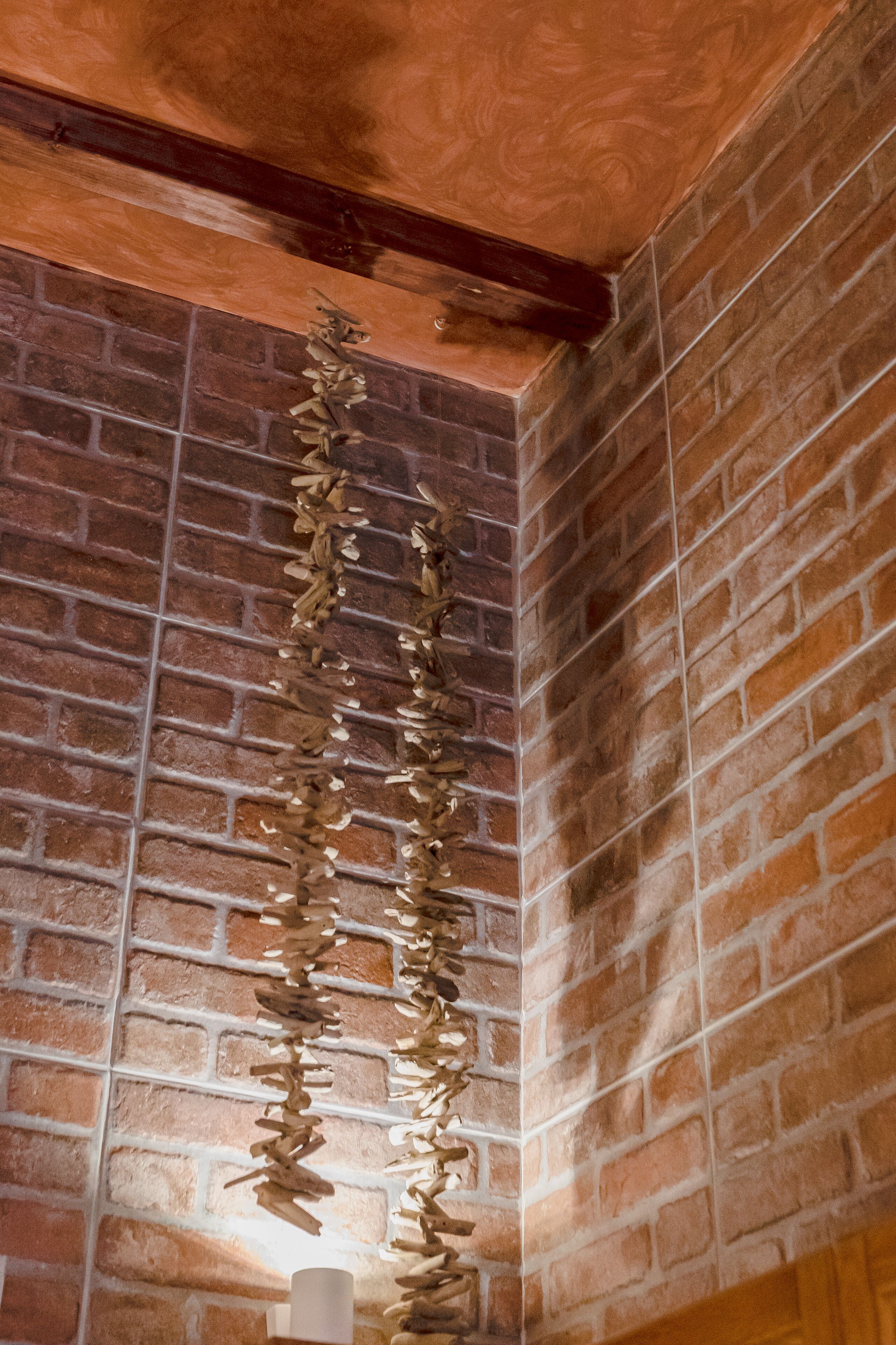 Un mur en briques avec un plafond en poutres apparentes et une guirlande décorative.