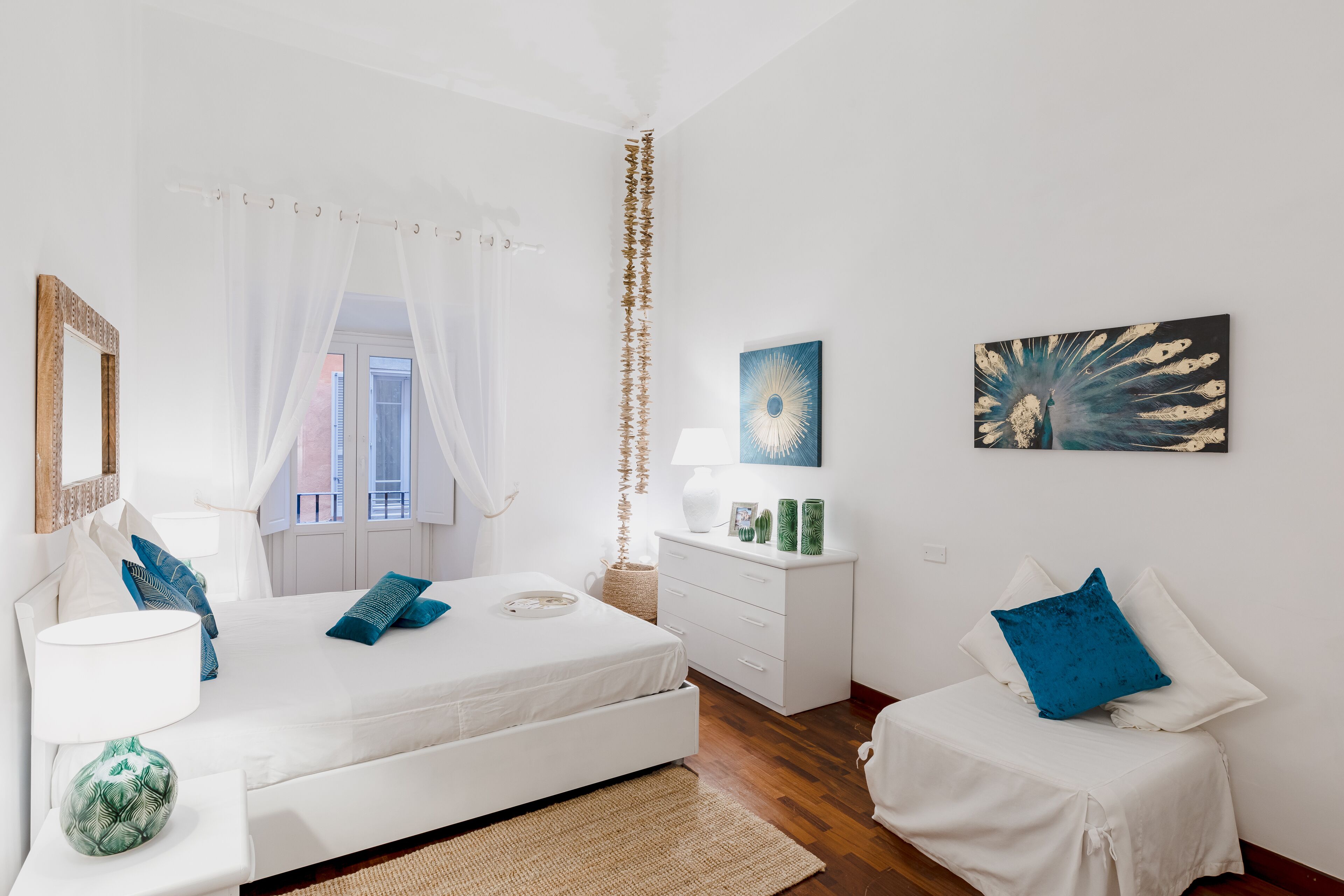 A bedroom with a bed, bedside tables, a dresser, and a window with curtains.