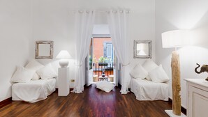 Una habitación con piso de madera, muebles blancos y vistas a través de un vano.
