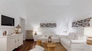 Una sala de estar moderna con un sofá blanco, un televisor montado en la pared y un adorno decorativo.