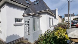 Ein zweistöckiges Haus mit grauer Fassade, einer kleinen angebauten Garage und einem sichtbaren Fenster.