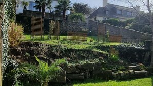 Ein gepflegter Garten mit Steinmauer, Holzpforte und einer Bank.