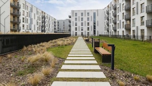 Un moderno complejo de apartamentos con un camino central que lleva a un banco.