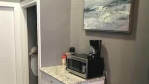 A compact kitchen with a microwave, refrigerator, and a painting on the wall. - Bay VIllage Suite, Ready To Host! (Boston)