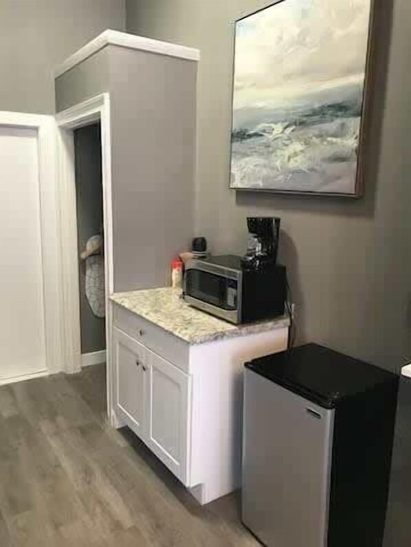 Une cuisine de taille réduite, équipée d’un four à micro-ondes, d’un réfrigérateur et ornée d’un tableau au mur.