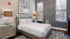 A bedroom with a large bed, a nightstand, a desk, and a chair. - Bay VIllage Suite, Ready To Host! (Boston)