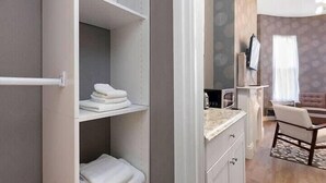 A hotel room with a built-in closet, a small kitchenette, a seating area with a chair, and a large window with curtains. - Bay VIllage Suite, Ready To Host! (Boston)