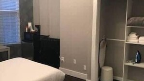 Um quarto com cama, mesa de cabeceira, armário e janela com persianas.