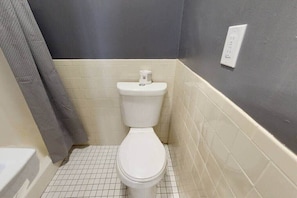 A small bathroom with a white toilet, a towel hanging on the wall, and a tiled floor. - Private Studio In Boston's Bay Village! (Boston)