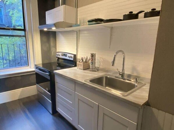 A modern kitchen with a stainless steel sink, a stove, and a window providing a view of the outdoors.
