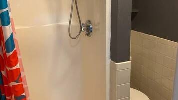 Ein Badezimmer mit Dusche, Toilette und Fliesenboden.