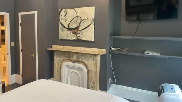 Een slaapkamer met een bed, een open haard, een wandtelevisie en een luchtzuiveraar.