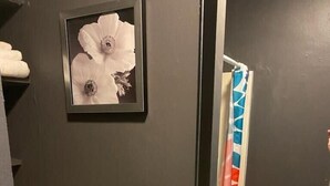 A bathroom with a white sink, a framed picture on the wall, and a towel rack.