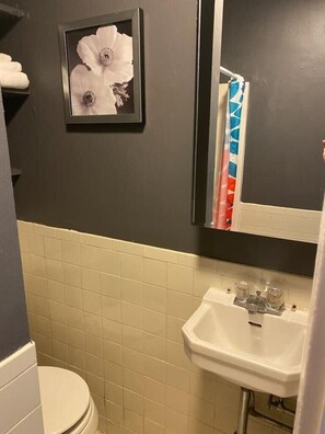 A bathroom with a toilet, a sink, and a framed flower picture on the wall.