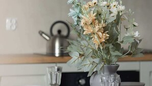 Une table à manger avec un vase de fleurs, deux bols et un verre.