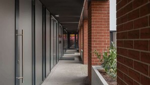 A corridor with a brick wall on one side and glass doors on the other. - Modern Studio in the Center | Balcony and Workspace (Poznan)