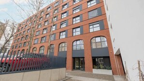A multi-story building with a brick facade, large windows, and a gated entrance. - Modern Studio in the Center | Balcony and Workspace (Poznan)