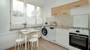 A compact kitchen with a washing machine, microwave, stove, and a dining area with a table and chairs.