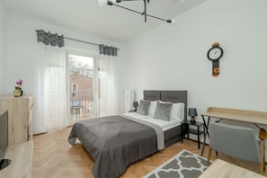 Ein modernes Schlafzimmer mit Bett, Nachttischen, einem Schreibtisch und einer Wanduhr.